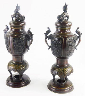A pair of 19thC Japanese bronze vases and covers, with cast dog of fo finial, each with two ornate handles, the bodies decorated with flowers, leaves, birds, terminating in three scroll feet, on circular metal bases, 33cm high. (AF)