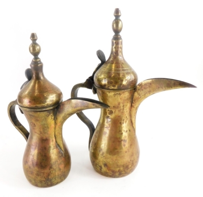 A pair of graduated Eastern metal ewers, with a shaped finial and long stem funnel, the largest 29cm high.