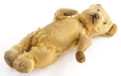 A mid 20thC caramel coloured Teddy bear, with beaded eyes and stitched snout, 36cm long. (AF)