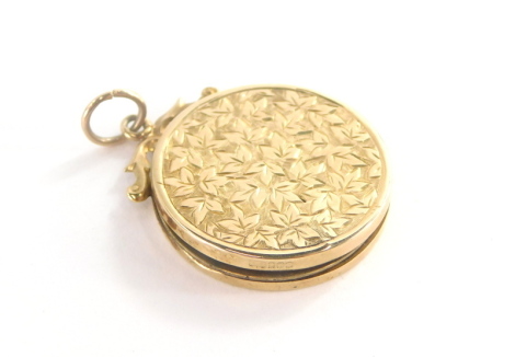 A circular locket pendant, marked with scroll pendant mounted top, and leaf design detailing, yellow metal unmarked, 2cm wide, 4.3g all in.