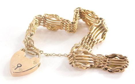 A 9ct gold gate bracelet, with hammered link detailing and interlinked five bar design, with heart shaped padlock on safety chain, 18cm long, 17.8g all in.