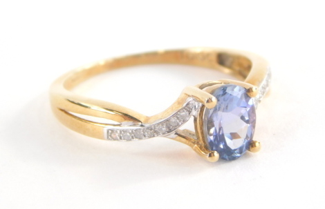 A modern dress ring, with central tanzanite type stone, and waved and twisted design shoulders set with tiny diamonds marked TGGC, hallmarked for 9ct but the band stamped 10k, ring size O, 2.2g all in.