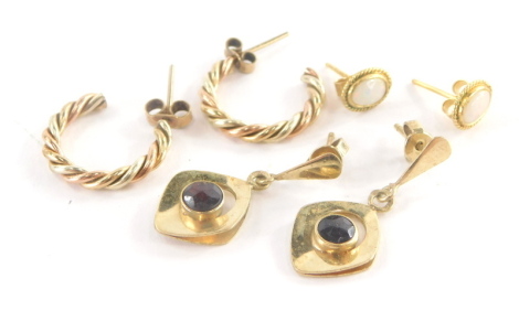 Three pairs of 9ct gold earrings, to include a pair of 9ct gold bi-colour hoop earrings, 1.5cm high, a pair of 9ct gold opal stud earrings, and a pair of 9ct gold and garnet set drop earrings, 7.4g all in. (3 pairs )