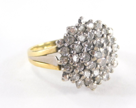 A 18ct gold diamond cluster ring, with four layers of tiny diamonds, each in platinum claw setting in a raised shank, on a yellow metal band, ring size I, 5.8g all in.