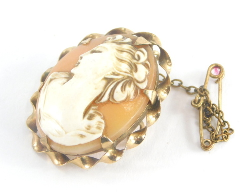 A 9ct gold framed shell cameo brooch, the oval shell raised cameo depicting figure of lady looking left, with waved design outer 9ct gold frame on safety chain, 2.5cm high, 6g all in.