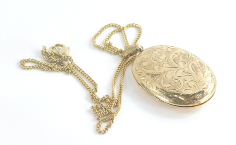 A 9ct gold locket pendant and chain, the oval locket with floral scroll engraving, and single loop pendant opening to reveal two photograph section, on a yellow metal longuard chain with large clip clasp stamped 9ct, the pendant 5.5cm high, the chain 54cm