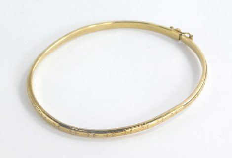 A silver hinged bangle, with star etched design, and safety clasp, yellow metal unmarked, 6cm diameter, 3.2g all in, boxed.