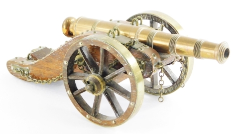 A model of an early 20thC cannon, in brass with a treen body, 36cm long.