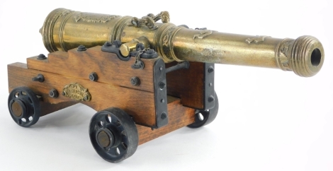 A reproduction brass table cannon of a Spanish El Tigre 1797 cannon, the body of the cannon cast with fish, armorial crest, design of scrolls, with a treen and cast metal frame, etc., 34cm long.