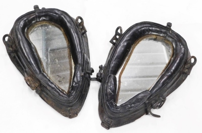 A pair of late 19th/early 20thC brown leather horse collars, each with metal mounts, converted into wall mirrors.