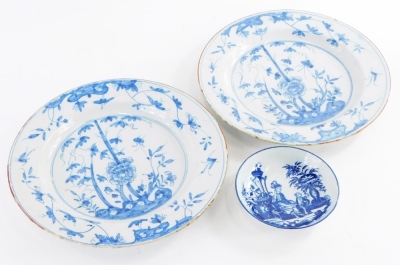 A pair of late 18th/early 19thC Delft plates, each decorated in Chinese style with blue flowers and leaves, within an iron red border, 26cm diameter, and a Caughley saucer, printed with an oriental pattern. (3)