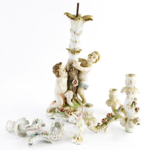 A continental porcelain three branch candelabrum, supported by two putti with flower encrusted base, the base 39cm high, (AF), and a continental porcelain figure of a lady. (AF)