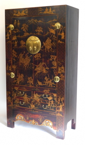 An oriental lacquered cupboard, decorated overall in raised gilt with warriors on horseback, and figures with mountainous landscapes, the two doors enclosing shelves with brass mounts above four drawers, the pierced apron carved with flower heads etc., on