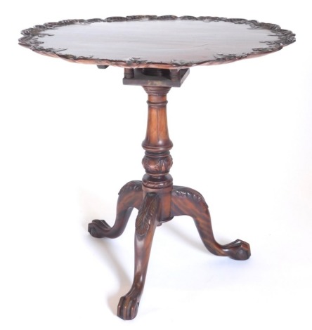 An oriental hardwood occasional table in George III style, the circular dished top carved with flowers, berries, etc., above a birdcage and a turned column on tripod base with ball and claw feet, 74cm diameter.