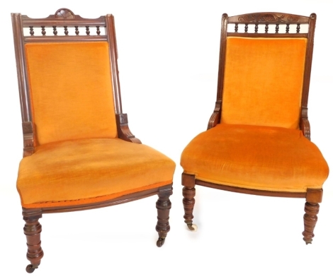 Two similar late 19thC walnut ladies or nursing chairs, each with an orange upholstered padded back and seat, on turned legs.