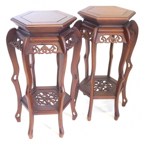 A pair of oriental hardwood urn stands, each with a octagonal top, a pierced frieze and an undertier, 67cm high.