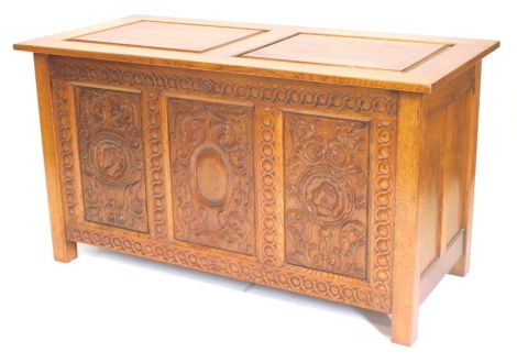 A carved oak coffer, with panelled top on stiles, 129cm wide.