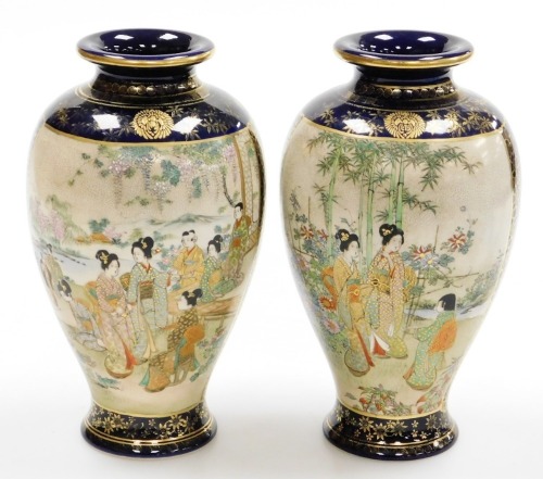 A pair of early 20thC Japanese Satsuma baluster vases, with panels of geishas at leisure in a garden, on a blue ground with gilt floral and diaper decoration, signed to base, 25cm high.