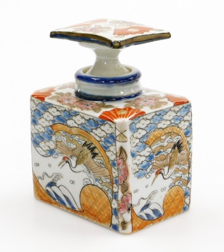 A Japanese Meiji period Arita porcelain bottle and stopper, of rectangular section, decorated with panels of cranes waves and flowers, 13cm high.