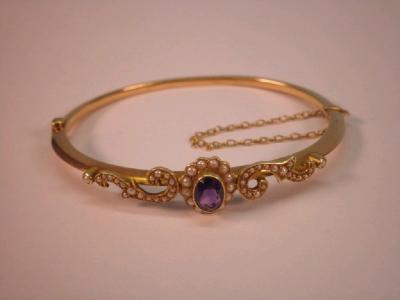 A Victorian hinged bangle with amethyst and seed pearl set central oval