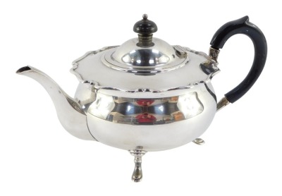 A George V silver teapot, with fluted top and ebonised knop and handle, on tripod base, makers stamp Sheffield 1923, 20oz gross. (AF)