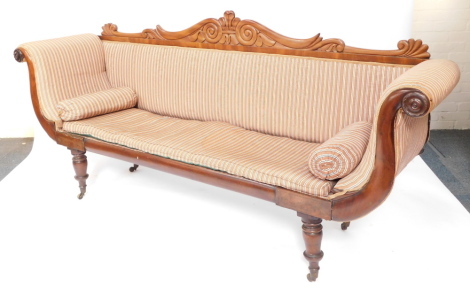 A Regency flame mahogany scrolling sofa, with a foliate carved back, blue and white patterned fabric, raised on turned legs, brass capped on castors, 225cm wide.