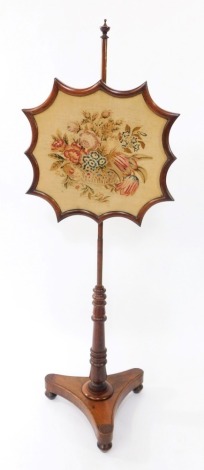 An early Victorian rosewood firescreen, the shaped screen with wool work floral tapestry, raised on a turned column, over a trefoil base, on three turned feet, 149cm high.