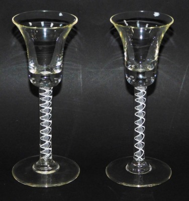 A pair Georgian style spiral twist wine glasses, the trumpet shaped bowls with air bubble inclusions, on straight opaque air twist stems, over conical feet, 18cm high. (2)