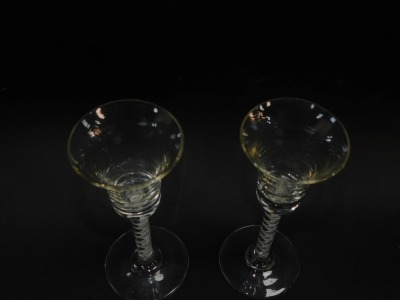 A pair Georgian style spiral twist wine glasses, the trumpet shaped bowls with air bubble inclusions, on straight opaque air twist stems, over conical feet, 18cm high. (2) - 2