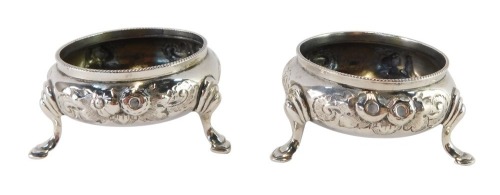 A pair of Victorian silver circular salts, with embossed floral decoration, raised on three hoof feet, Robert Harper, London 1866, 3¼oz.