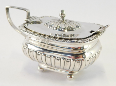 An Edward VII silver mustard and plated spoon, the pot of semi fluted form, on four bun feet, with blue glass liner, Birmingham 1906, 2¾oz of weighable silver.