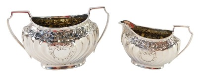 A Victorian silver sugar bowl and cream jug, each semi fluted with chased silver rose detailing and vacant shield, Atkins Brothers, Sheffield 1889, 8¼oz. (2)