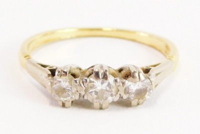 An 18ct gold and platinum three stone diamond ring, set with three old cut diamonds, with platinum claw setting, with Art Deco style shoulders, on a yellow metal band, size P½, 2.6g all in.