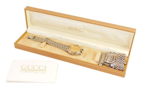 A Gucci Timepieces wristwatch, with circular dial, and outer gold plated finish, with Gucci symbols, on a stainless steel back, No 9000M., with loose bracelet links in Gucci Timepieces box, card certificate of origin.