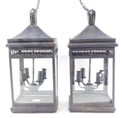 Two wrought iron hanging lanterns, each with four branch central panel, with hanging chain, converted to electricity, 55cm high.