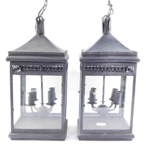 Two wrought iron hanging lanterns, each with four branch central panel, with hanging chain, converted to electricity, 55cm high.