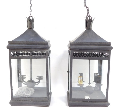 Two wrought iron hanging lanterns, each with four branch central panel, with hanging chain, 55cm high.