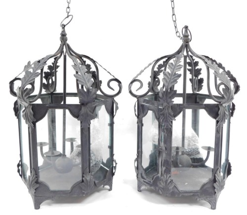 Two wrought iron hanging lanterns, each hexagonal with four branch central candle stand, with acanthus leaf detailing, on hanging loop, 56cm high. (2)