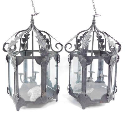 Two wrought iron hanging lanterns, each hexagonal with four branch central candle stand, with acanthus leaf detailing, on hanging loop, 56cm high. (2)