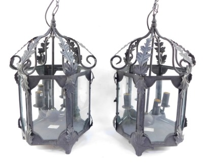 Two wrought iron hanging lanterns, each hexagonal with four branch central candle stand, with acanthus leaf detailing, on hanging loop, 56cm high. (2)