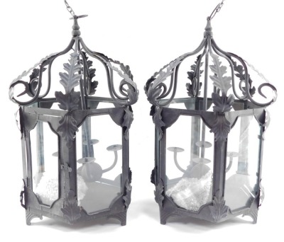 Two wrought iron hanging lanterns, each hexagonal with four branch central candle stand, with acanthus leaf detailing, on hanging loop, 56cm high. (2)