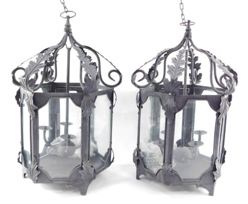 Two wrought iron hanging lanterns, each hexagonal with four branch central candle stand, with acanthus leaf detailing, on hanging loop, 56cm high. (2)