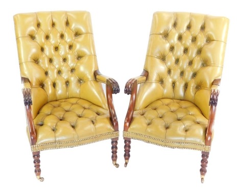 A pair of Chesterfield style mahogany and leather arm chairs, each with a lime green buttoned back, and mahogany arms, on turned legs, brass capped on castors, 102cm high, 58cm wide, 70cm deep.