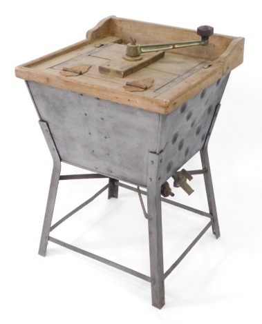 An early 20thC manual washing machine, with wooden frame and turned metal handle on galvanised bucket, on four claw base with taps, 80cm high, 52cm wide, 55cm deep.