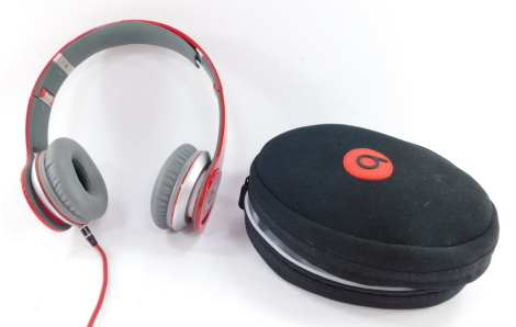 A set of Beats solo HD wired headphones, in red with carry case.