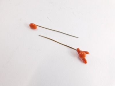 Two coral stick pins, one of wishbone design with central circular panel, the other with single oval coral, each on a steel pin in Barron Clark and Son of Boston box. (2) - 2