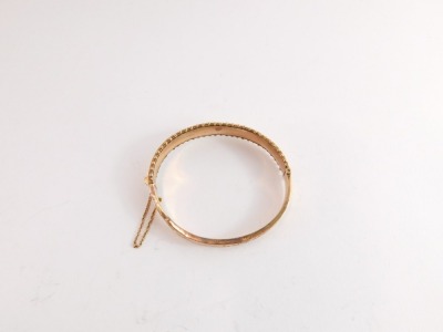 A 9ct gold hinged bangle, with two part floral detailing and half hinged outer filigree bordering, with safety chain, 6.5cm wide, 8.9g all in. - 2