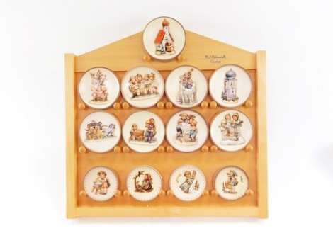 A group of Goebel Hummel collector's plates, on collector plate stand, to include Nos 1078., 1402., 1406., 1295., 1414., 1286., 1410., 1408., 1401., 1150., 1403., 1412 and 1409, on a modern pine rack, the plates boxed, 46cm high, 46cm wide.