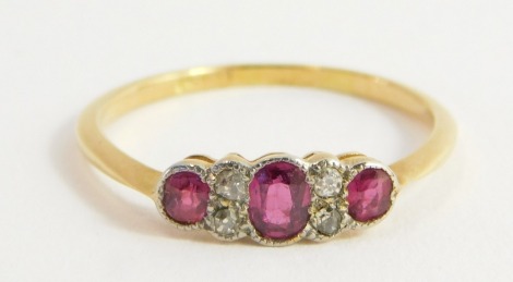 An 18ct gold and ruby three stone ring, set with pairs of diamonds at intervals, size Q½, 2.2g.