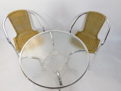 A chrome and glass garden bistro table, with a mottled glass top, with circular centre section on a chrome base, with two cane weaved chairs, 72cm high, 71cm diameter. (3) - 2